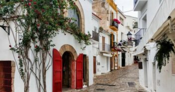Das Glückshotel Ibiza kann führt auf eine Insel mit vielen überraschenden Facetten. Die Altstadt von Ibiza mit ihrem Kopfsteinpflasteer, den weißen Wänden ist oft sehr romantisch. Eivissa, wie die Katalanen das Kleinod nennen besticht auf diesem Foto mit pittoreskem Flair des Mittelmeers. Wuchernder Efeu, leuchtend rote Türen an weißen Häuserwänden - einfach eine malerische Altstadt.